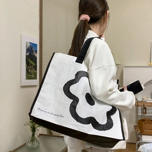 Detail of floral woven tote bag featuring black flower print and side view on shoulder