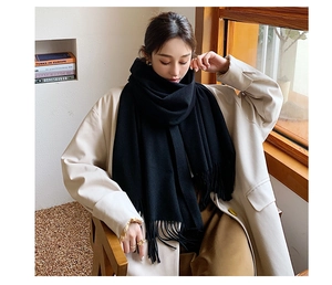 Detail of soft black cashmere-feel scarf showing its thick texture and classic fringe tassels