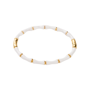Close-up of bamboo-style stainless steel bangle with white enamel and golden metal accents