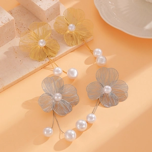 Detailed shot of hollow flower earrings with pearl tassels in gold and silver finishes