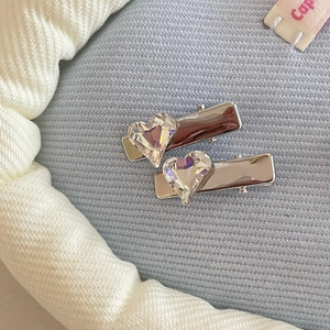 Macro shot of silver metal hair clips featuring sparkling heart-shaped crystal detail
