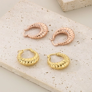 Elegant oval titanium steel hoop earrings with gold spiral texture on stone pedestal