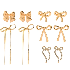 Detail view of five pairs of gold bow earrings featuring textures and rhinestone accents