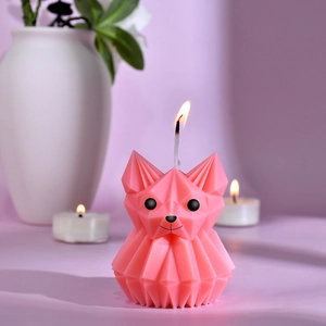 Pink origami geometric dog scented candle with a flickering flame on a modern base