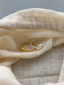 Detailed close-up of gold and silver minimalist bead rings on soft fabric background