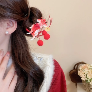 Close-up of Chinese New Year koi embroidery hair clip with red pompoms and gold coin charm