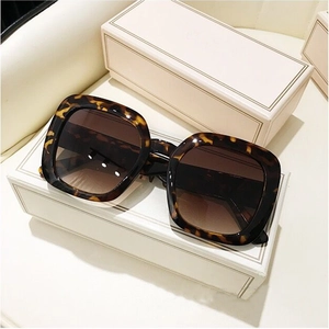 Detail of square oversized tortoise shell sunglasses with gradient brown lenses on a box