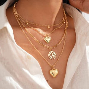 Detail of layered gold necklace featuring double heart pendants and round map charm