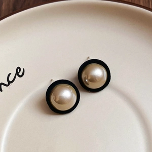 Detailed view of vintage flocking pearl studs on a cream ceramic plate with soft shadows