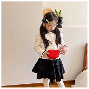 Girl wearing a red heart-shaped quilted chain bag with white jacket and black skirt