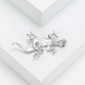 Elegant silver gecko brooch with natural abalone shell inlay on white geometric background