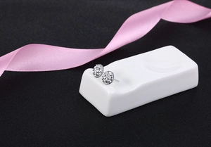 Detail of silver S925 round stud earrings with sparkling crystals on ceramic base