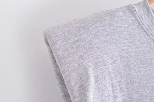 Dettaglio ravvicinato di t-shirt grigia con girocollo a costine e cuciture spalle