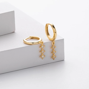 Gros plan sur des boucles d'oreilles dorées avec trois pendentifs étoiles en cristal brillant