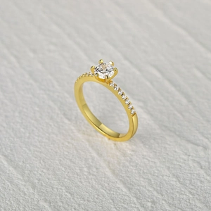 Classic gold S925 sterling silver four-prong solitaire ring with side stones on gray background