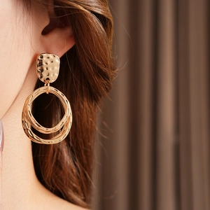 Detail of gold geometric earrings with hammered texture and double round hoops on a model