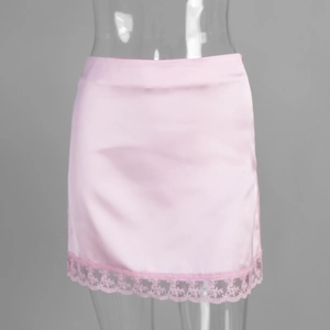 Close-up of pink satin mini skirt featuring delicate floral lace trim at the hemline