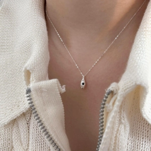 Close-up of a silver 925 water drop pendant necklace with black zircon on a knit sweater