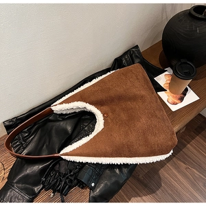 Brown suede tote bag with white faux fur trim placed on a wooden bench in a cozy setting