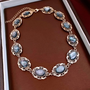 Detailed view of a vintage gold necklace with oval dark resin stones in a jewelry box