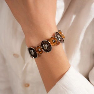 Détail d'un bracelet bohème en argent avec breloques en résine ambrée au poignet