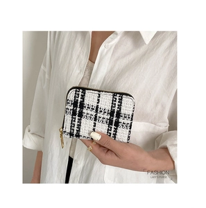 Close-up of black and white tweed coin purse with a premium gold zipper detail