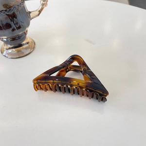 Detailed view of tortoise shell triangular hair claw clip with golden metal spring