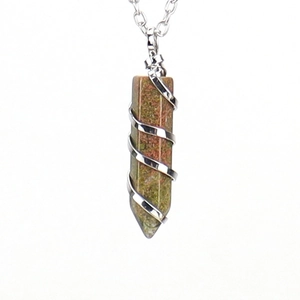 Macro view of unakite crystal hex prism with silver spiral wire wrap and cross chain