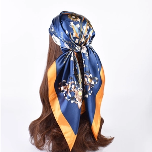 Detail of floral silk scarf in navy blue and orange tied on a brown hair model