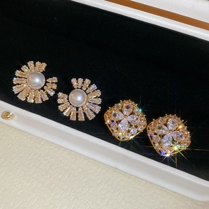 Macro shot of gold-plated pearl sunflower and zircon floral studs on a black velvet display