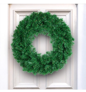 Detail of lush green PVC artificial Christmas wreath hanging on a white wooden door