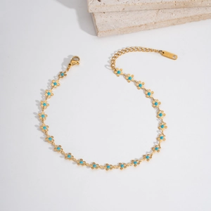 Detail of stainless steel anklet with gold flower links and turquoise stones