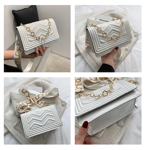 Detail view of white quilted crossbody bag with gold chain and patterned wide strap
