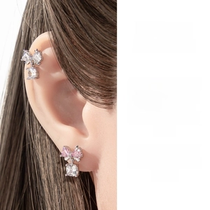 Close-up of bow-knot zircon pendant earrings worn on the earlobe and cartilage