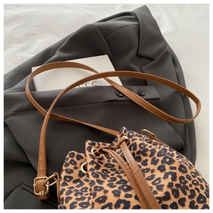 Détail du sac seau imprimé léopard avec cordon en cuir marron et bandoulière