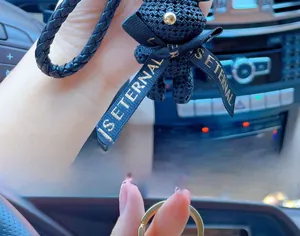 Detail of woven resin bear keychain with gold IS ETERNAL ribbon and luxury metal ring