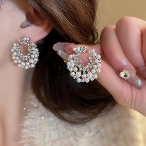 Boucles d'oreilles géométriques élégantes avec perles et strass portées par un mannequin