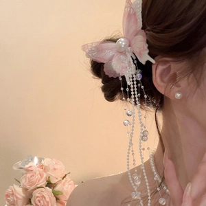 Detail of pink butterfly hair clip with long pearl tassels worn by a model for a romantic look