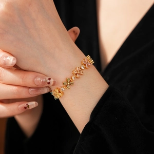 Detail eines eleganten Kleeblatt-Armbands mit bunten Zirkonia am Handgelenk einer Frau