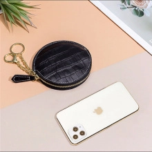 Detail of round black faux crocodile leather coin purse with gold zipper and chain hook