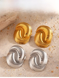 Detailed view of gold and silver shell-shaped stud earrings on sand texture
