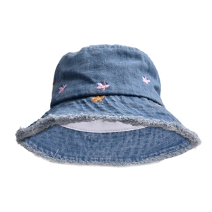 Close-up of embroidered flowers and frayed edges on blue denim bucket hat detail
