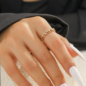 Nahaufnahme eines herzförmigen Goldrings mit Zirkonia-Steinen an einer Hand