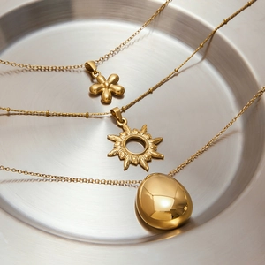 Elegant 18k gold stainless steel necklaces with flower and sun pendants on a tray