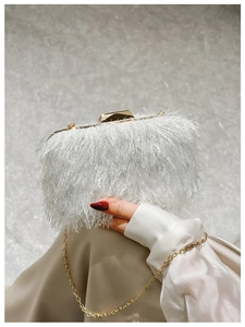 Detail of white fringe evening bag with gold geometric clasp and fine metal chain strap