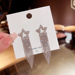 Macro shot of silver tassel earrings with star design and dangling crystal chains