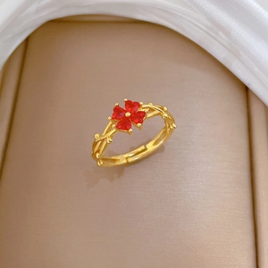 Détail de la bague trèfle dorée avec pierres cœur rouges et anneau texturé vigne