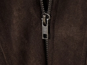 Gros plan du zip métallique et de la texture en daim marron café sur la veste