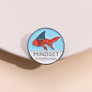 Macro detail of enamel pin with red koi and shark fin, featuring Mindset Is Everything text