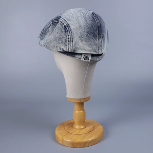 Detail of washed light blue denim flat cap with NARA brand label and vintage texture